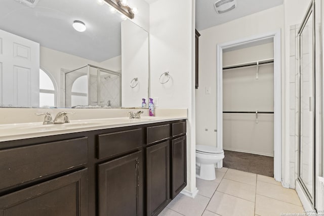 bathroom featuring a shower with door, vanity, tile patterned floors, and toilet