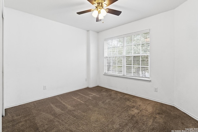 unfurnished room with ceiling fan and dark carpet