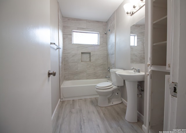 bathroom featuring toilet, tiled shower / bath combo, and wood-type flooring