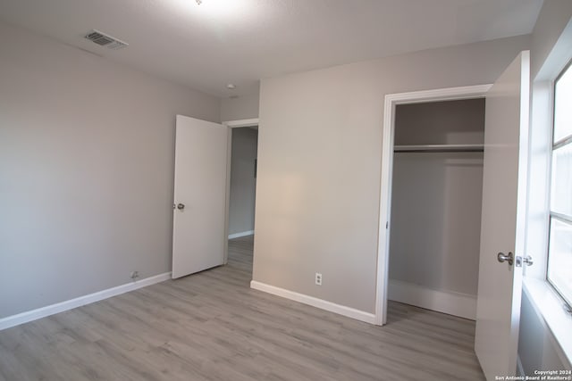 unfurnished bedroom featuring a closet and light wood-type flooring