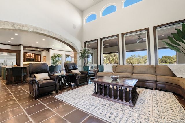 living room with dark tile patterned flooring, ceiling fan, a towering ceiling, and a wealth of natural light