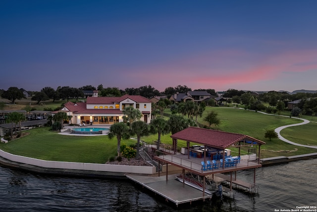 back house at dusk with a gazebo, a yard, and a water view