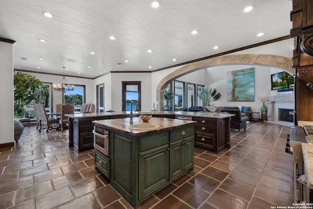 kitchen with hanging light fixtures, stainless steel oven, a kitchen island, an inviting chandelier, and sink