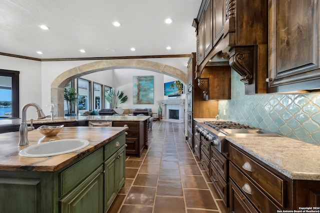 kitchen featuring crown molding, a center island, sink, and light stone counters