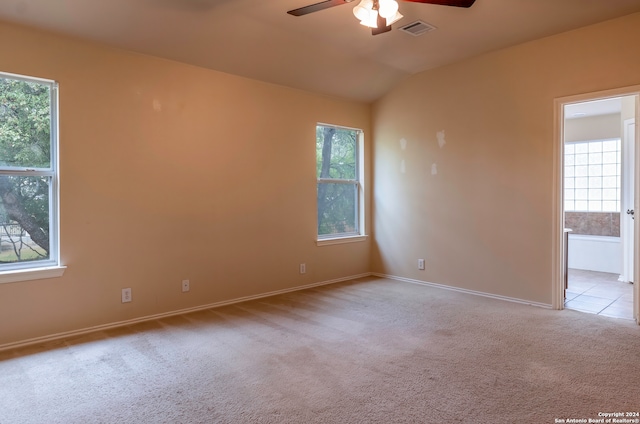 empty room with ceiling fan, a wealth of natural light, and light colored carpet