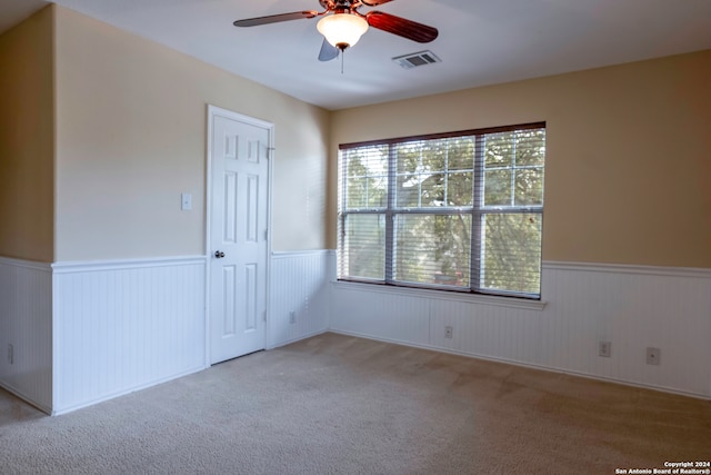 empty room with light colored carpet, a healthy amount of sunlight, and ceiling fan