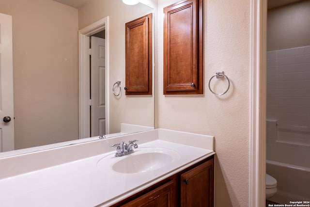 bathroom featuring toilet, vanity, and a bath