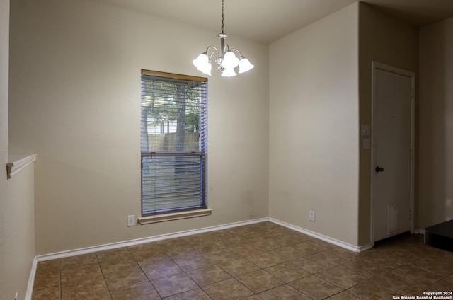 10707 Axis Xing, San Antonio, TX 78245 - unfurnished room with a chandelier, baseboards, and dark tile patterned floors