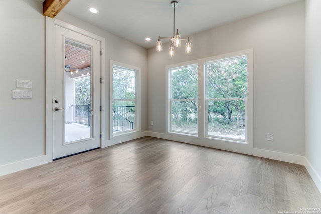 doorway to outside featuring a notable chandelier and light hardwood / wood-style flooring