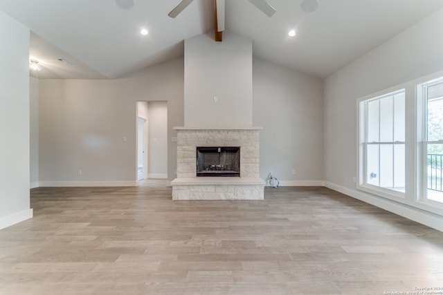 unfurnished living room featuring a stone fireplace, beamed ceiling, high vaulted ceiling, light wood-type flooring, and ceiling fan