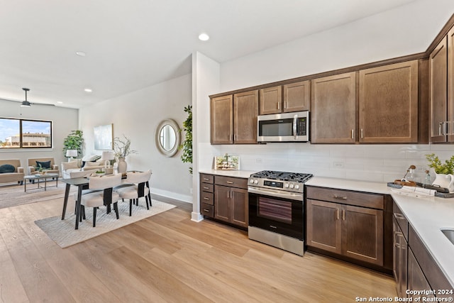 kitchen with dark brown cabinets, light hardwood / wood-style flooring, stainless steel appliances, and backsplash