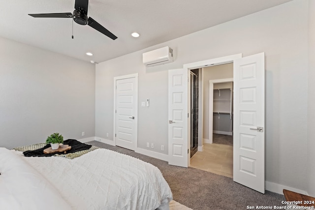 bedroom with carpet flooring, a wall mounted air conditioner, a spacious closet, a closet, and ceiling fan