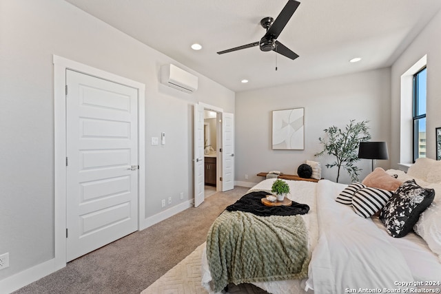 bedroom with a wall mounted air conditioner, ensuite bath, light colored carpet, and ceiling fan