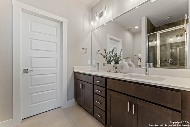 bathroom with a shower with door, vanity, and tile patterned floors