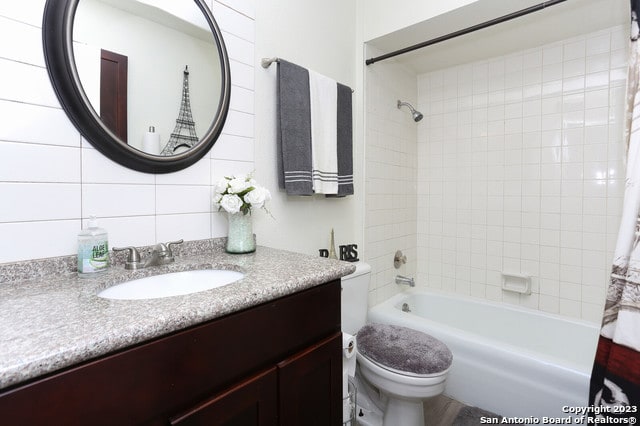 full bathroom featuring backsplash, toilet, tile walls, vanity, and shower / tub combo with curtain