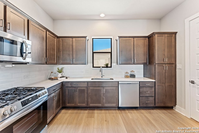 kitchen with sink, appliances with stainless steel finishes, light hardwood / wood-style flooring, and tasteful backsplash