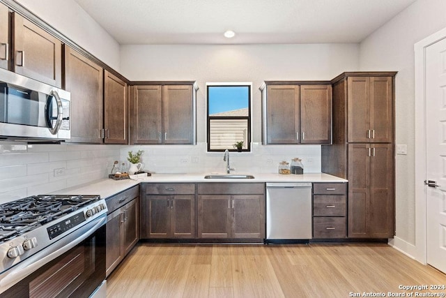 7942 Kennedy Hl Unit 8, San Antonio, TX 78235 - kitchen with stainless steel appliances, a sink, light wood-type flooring, light countertops, and backsplash