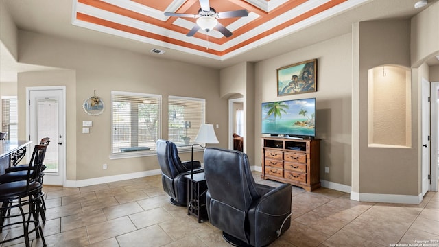 tiled living room featuring ceiling fan and a raised ceiling