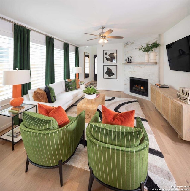 living room featuring a fireplace, light hardwood / wood-style flooring, and ceiling fan