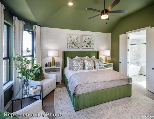 bedroom featuring light wood-type flooring, ensuite bath, lofted ceiling, and ceiling fan