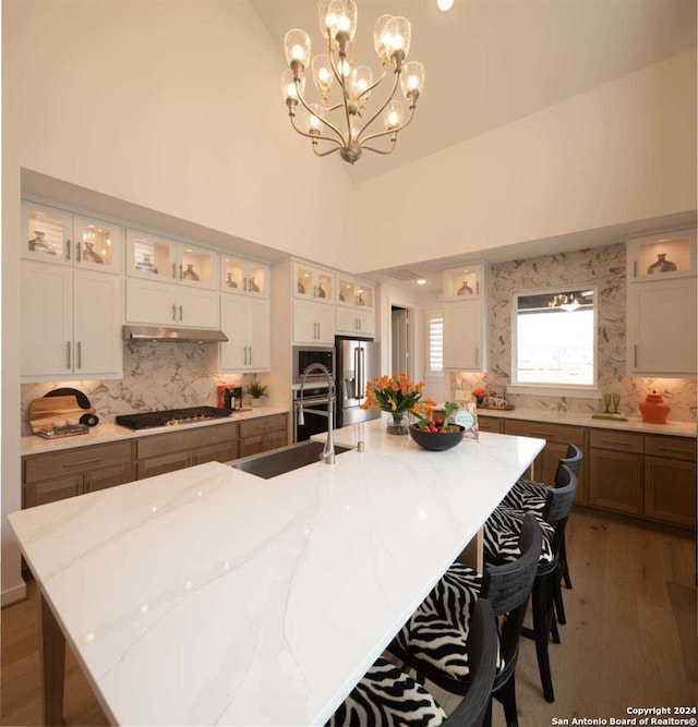 kitchen with a spacious island, dark hardwood / wood-style flooring, pendant lighting, and light stone countertops