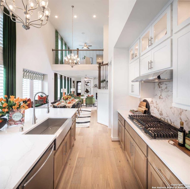 kitchen with white cabinetry, sink, light stone counters, appliances with stainless steel finishes, and pendant lighting