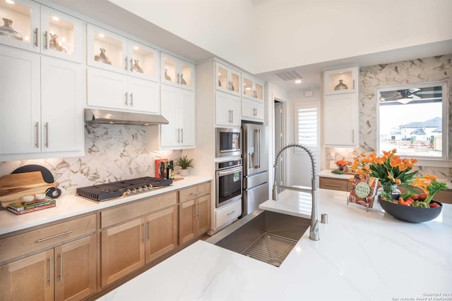 kitchen featuring white cabinetry, light stone counters, appliances with stainless steel finishes, and tasteful backsplash