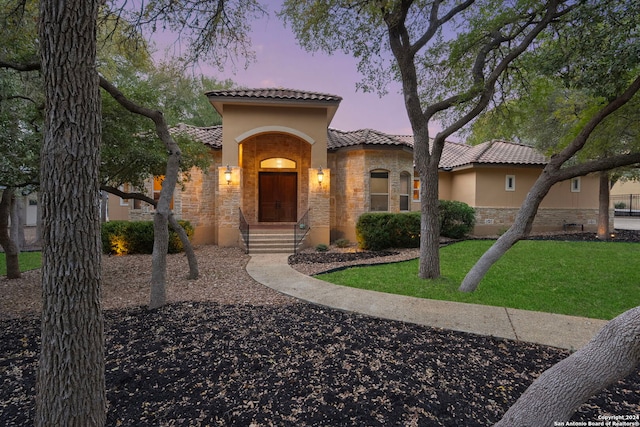 mediterranean / spanish home featuring a lawn