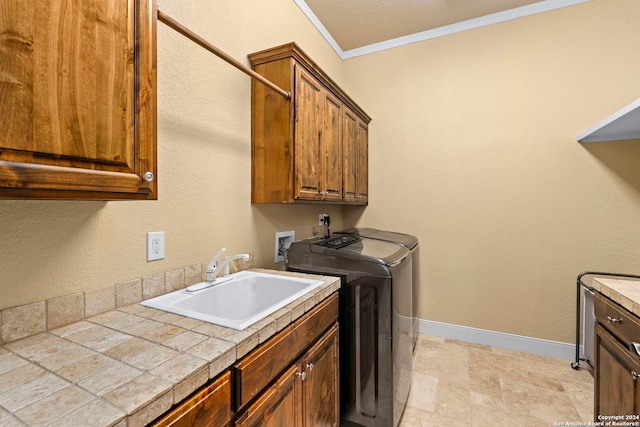 laundry room featuring cabinets, a textured ceiling, sink, crown molding, and washer and dryer