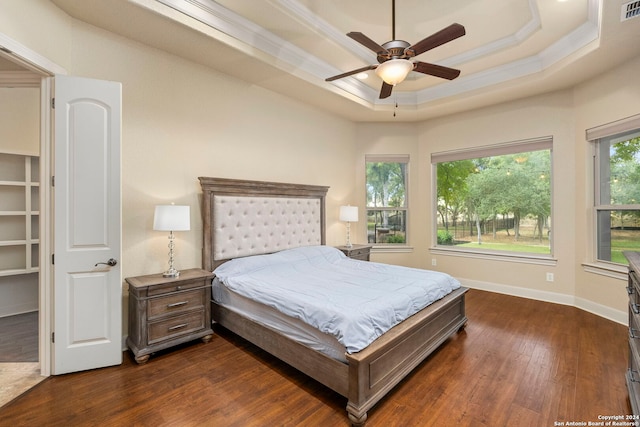 bedroom featuring ornamental molding, dark hardwood / wood-style flooring, ceiling fan, and a tray ceiling