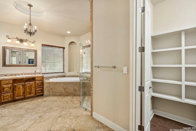 bathroom featuring a notable chandelier, vanity, a textured ceiling, and plus walk in shower