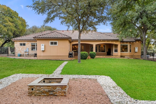 rear view of property with an outdoor fire pit and a lawn