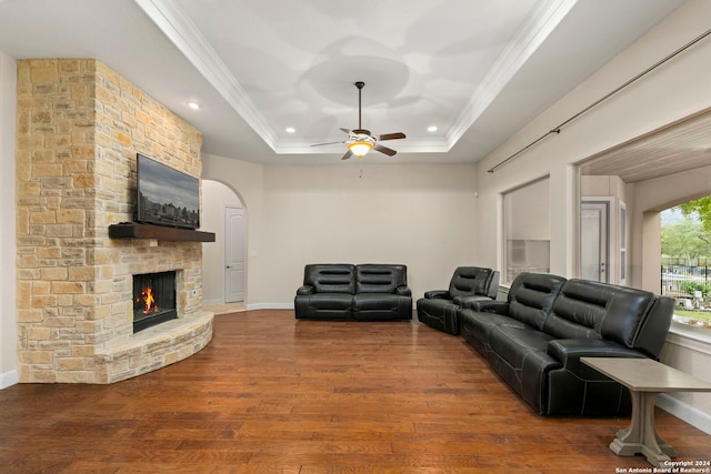 living room featuring a fireplace, crown molding, a raised ceiling, hardwood / wood-style flooring, and ceiling fan