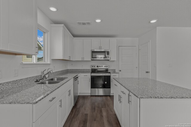 kitchen featuring white cabinets, light stone countertops, stainless steel appliances, and sink