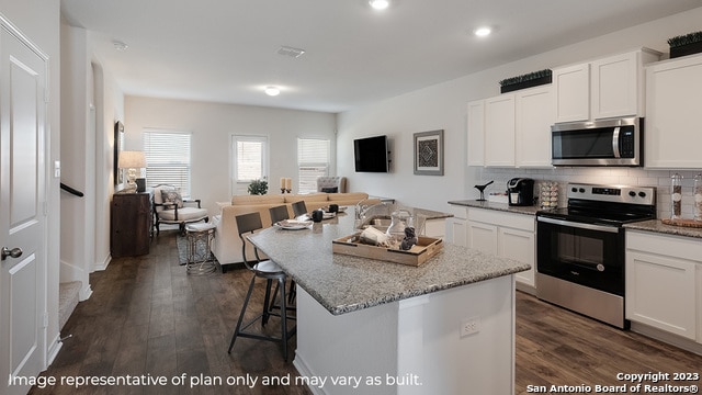 kitchen with dark hardwood / wood-style flooring, white cabinetry, an island with sink, and appliances with stainless steel finishes