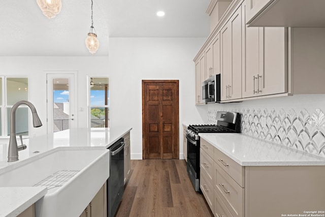 kitchen with light stone countertops, sink, dark wood-type flooring, pendant lighting, and appliances with stainless steel finishes