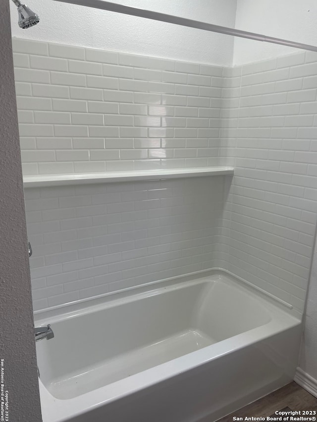 bathroom with hardwood / wood-style flooring and tiled shower / bath combo