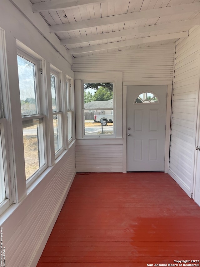 unfurnished sunroom featuring beam ceiling, a healthy amount of sunlight, and wooden ceiling