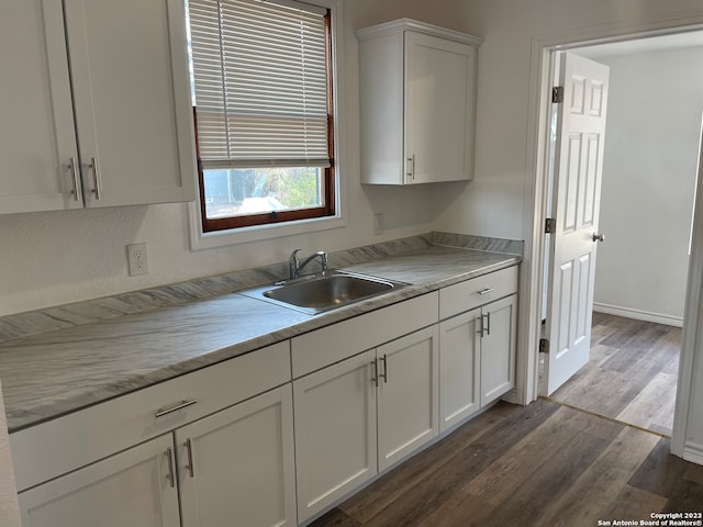 kitchen with white cabinetry, light stone countertops, wood-type flooring, and sink