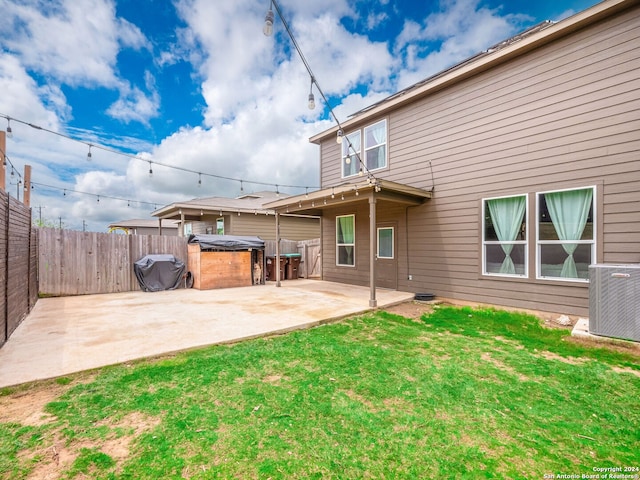 rear view of property featuring a jacuzzi, a patio area, a yard, and central AC unit