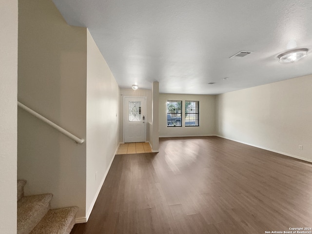 unfurnished living room with dark wood-type flooring and a textured ceiling