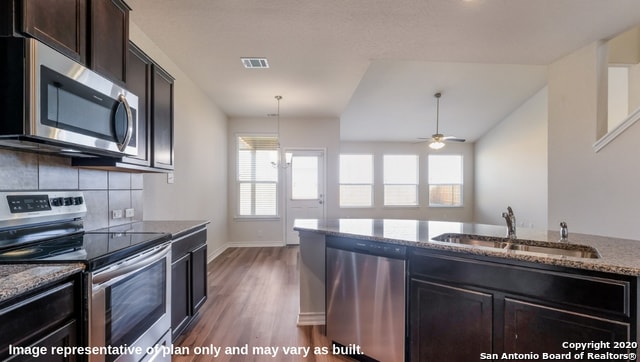 kitchen featuring light stone countertops, appliances with stainless steel finishes, sink, ceiling fan, and hardwood / wood-style flooring