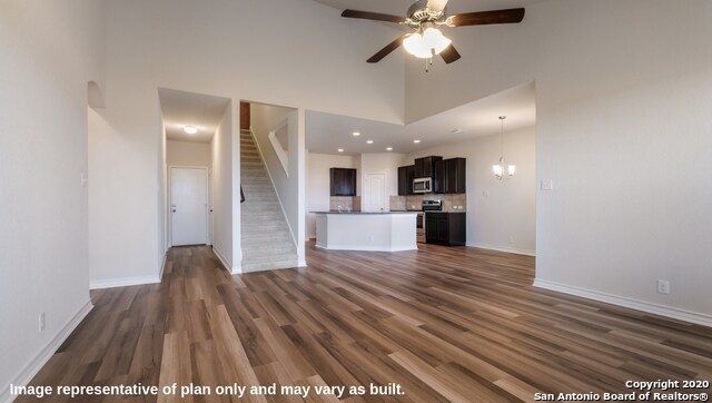 unfurnished living room with a high ceiling, ceiling fan, and dark hardwood / wood-style flooring