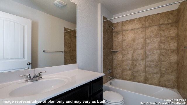 full bathroom featuring toilet, tiled shower / bath, and vanity