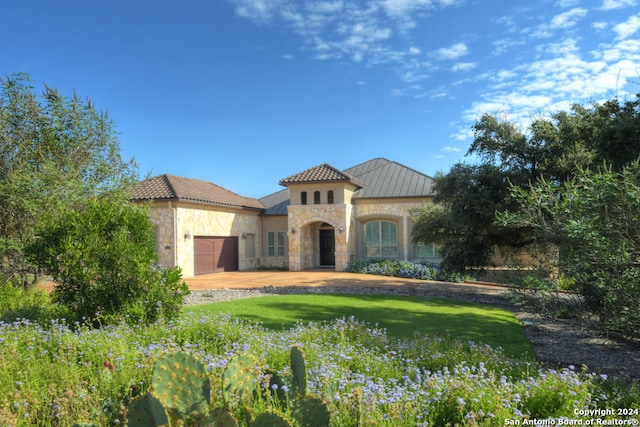 mediterranean / spanish house featuring a front yard and a garage