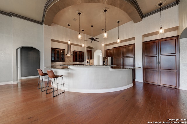 kitchen featuring dark wood-type flooring, high vaulted ceiling, and hanging light fixtures