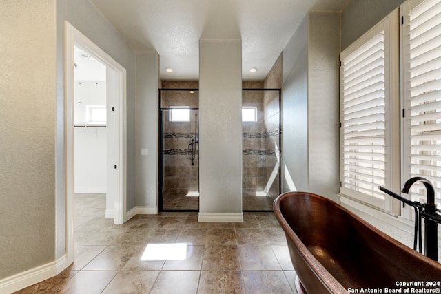 bathroom with a textured ceiling, independent shower and bath, plenty of natural light, and tile patterned flooring