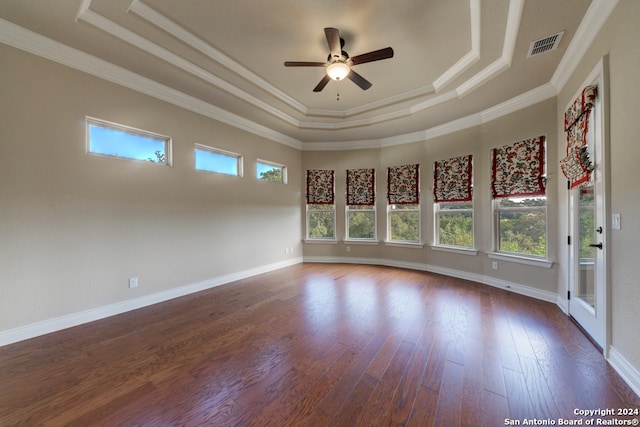 empty room with crown molding, dark hardwood / wood-style floors, a tray ceiling, and ceiling fan