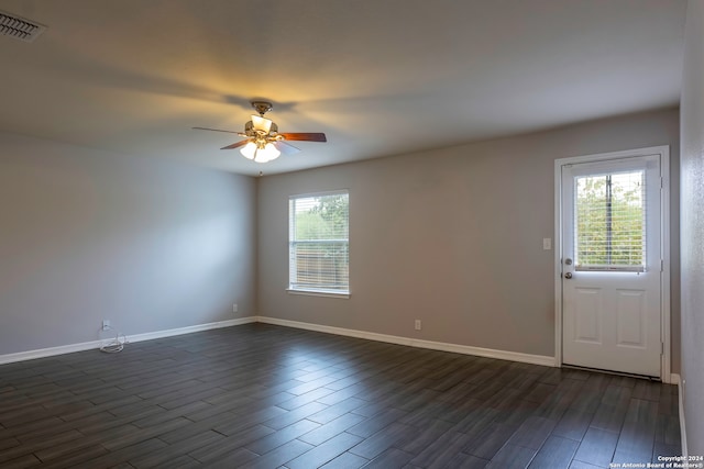 spare room with dark hardwood / wood-style flooring, ceiling fan, and plenty of natural light