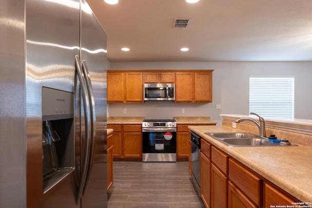 kitchen with appliances with stainless steel finishes, sink, and dark hardwood / wood-style flooring